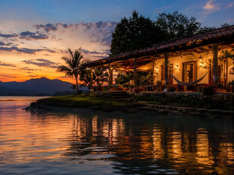 Lakeside Colombian finca terrace glowing at sunset on the Guatapé reservoir